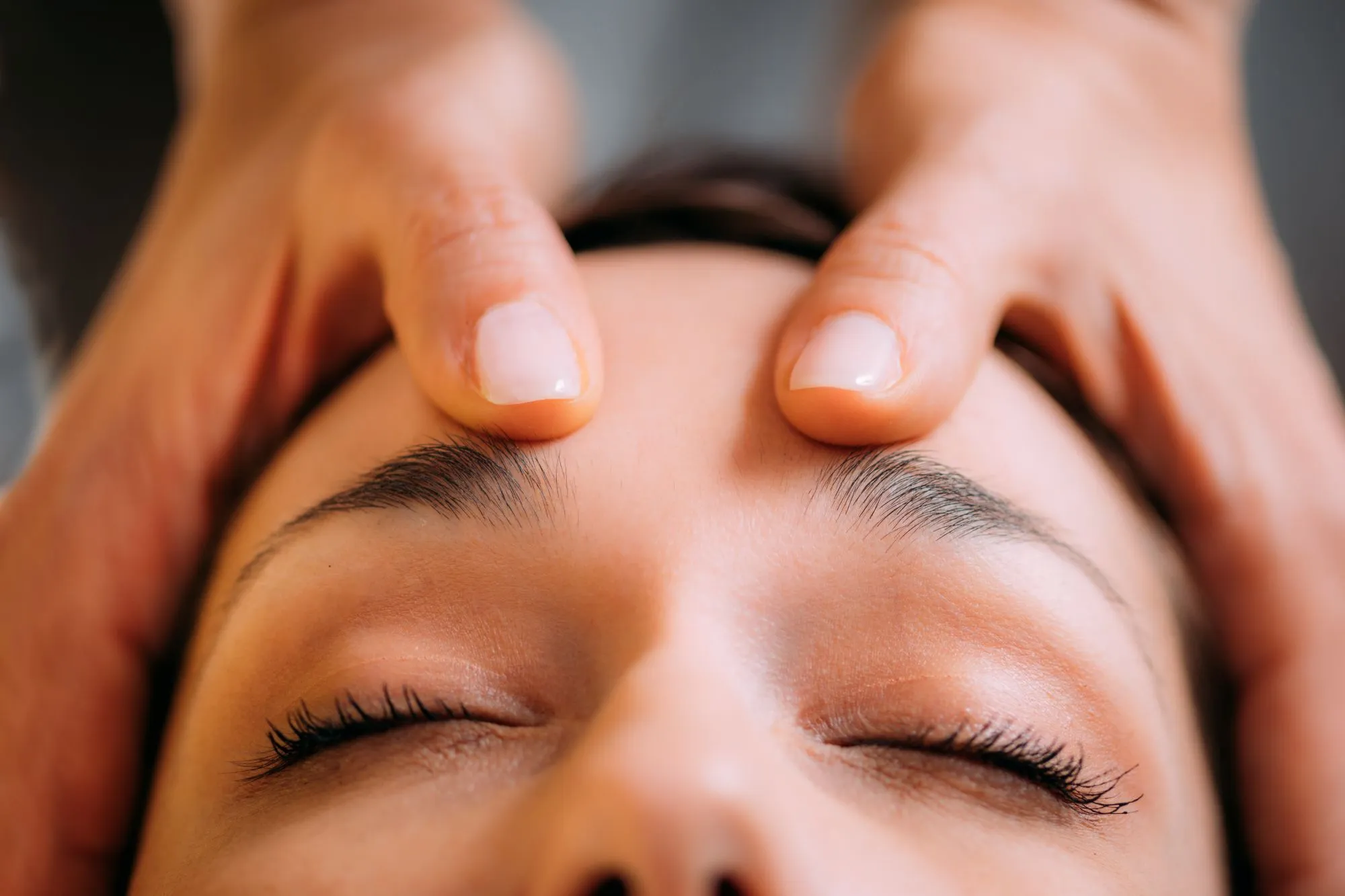 Client receiving craniosacral therapy beside a massage therapy treatment for stress-related symptoms